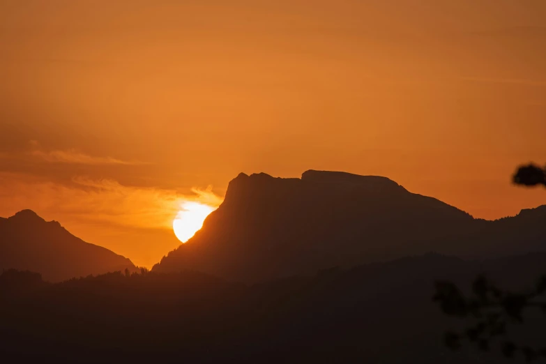 the sun is rising over mountains and a mountain top