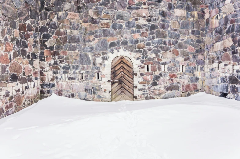 a door with a long window in an ancient stone wall