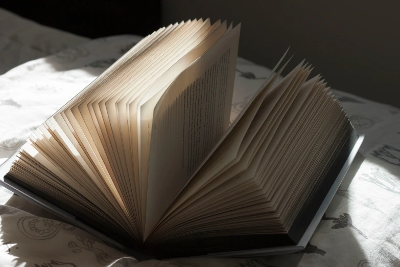 an open book on a bed with a white cover