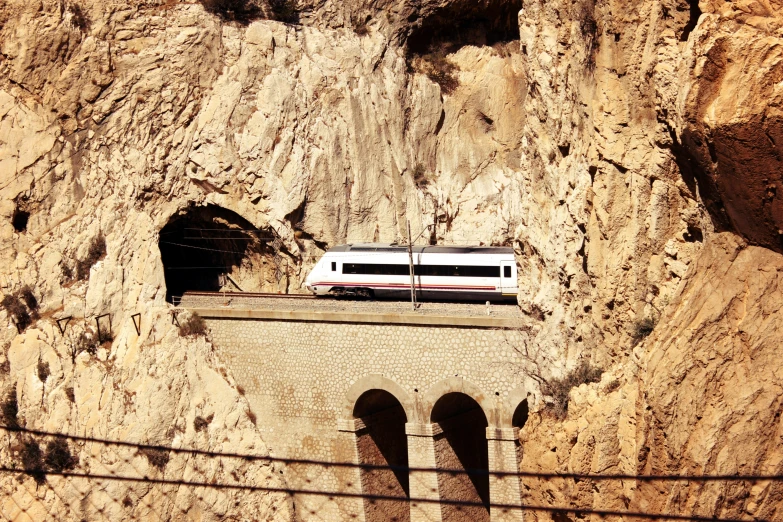 a train traveling along tracks near the side of a rocky cliff