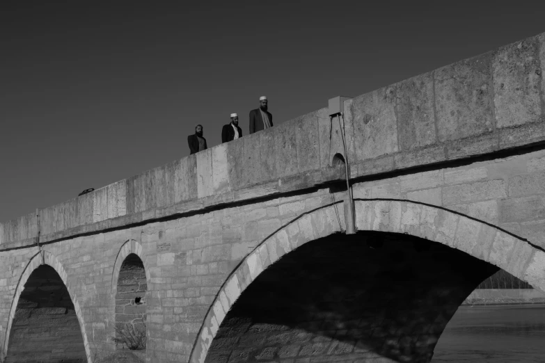 some people stand on a large bridge while others look off