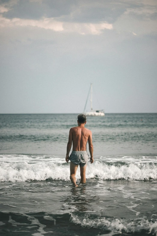 the man walks through shallow water towards the beach