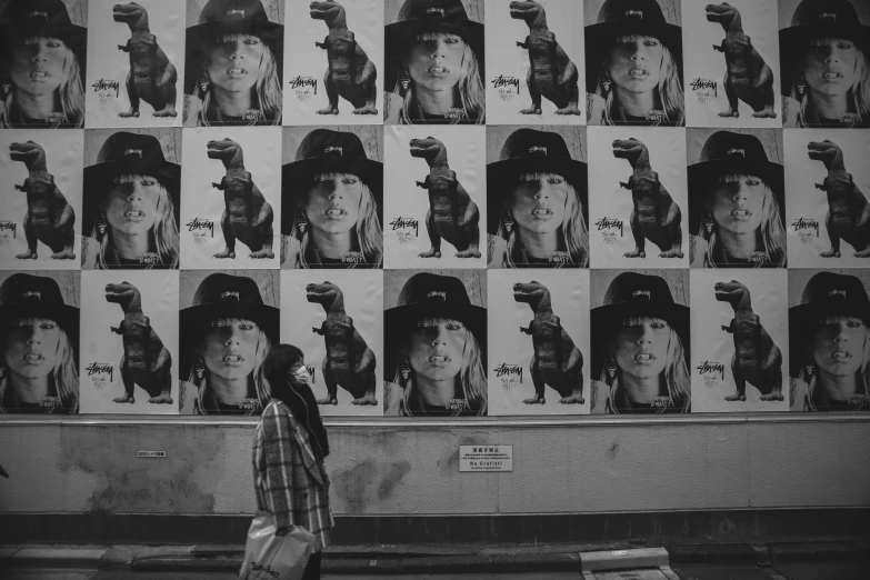 a woman walking past pictures of different people on display