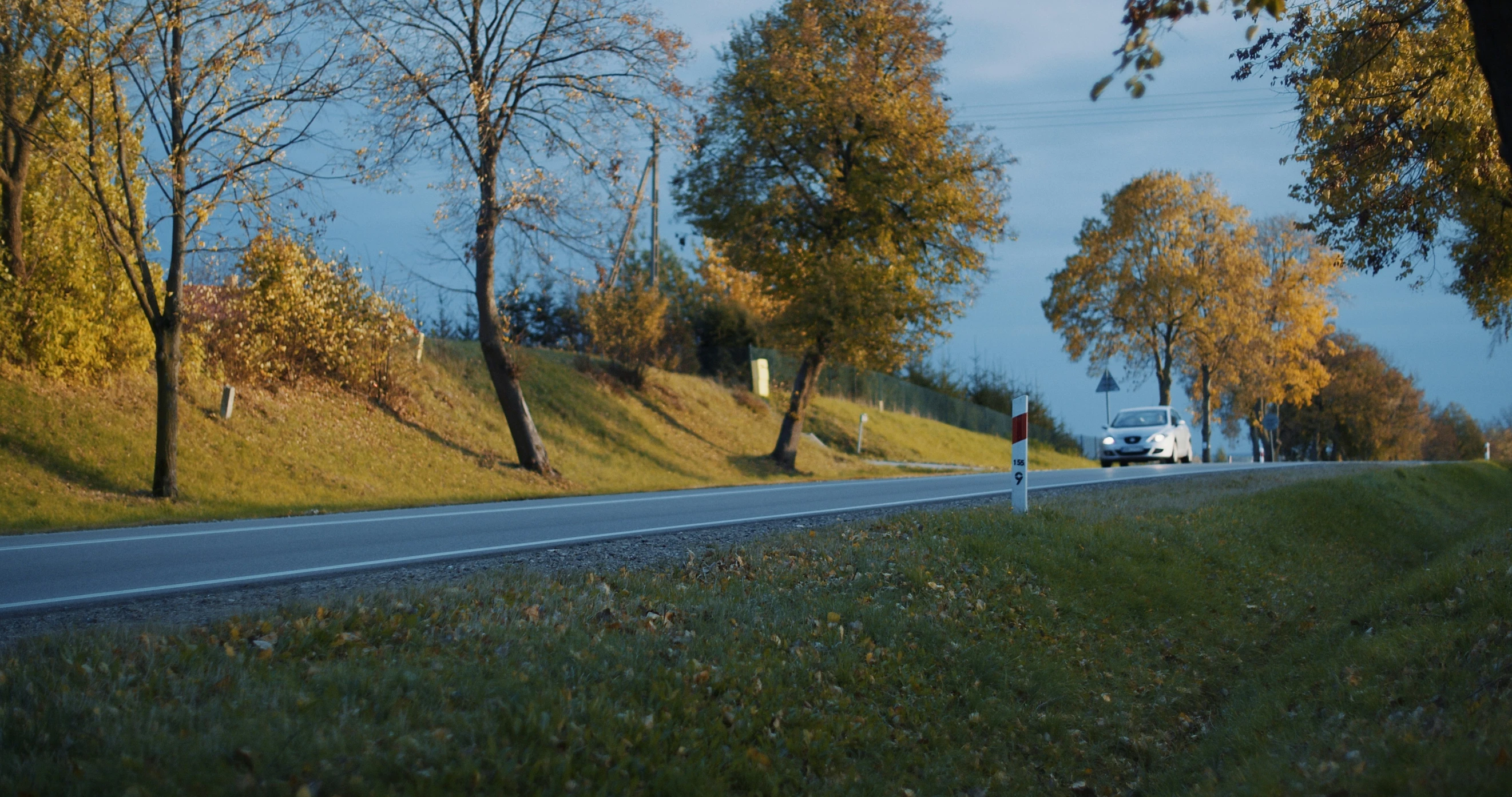 the car is driving down the empty country road