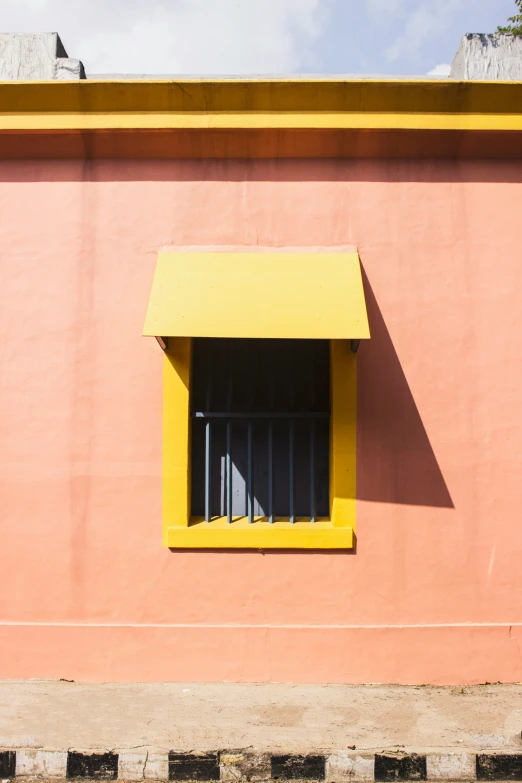 there is a yellow window on a building with bars on the sides