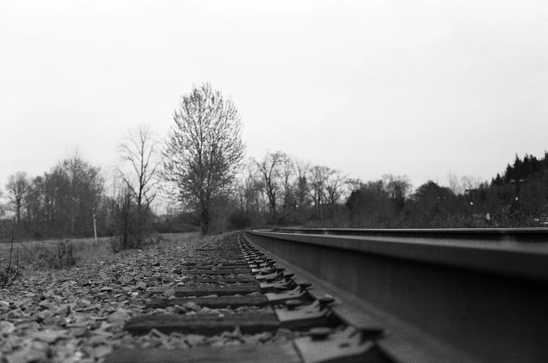 some train tracks on a cloudy day with trees in the distance