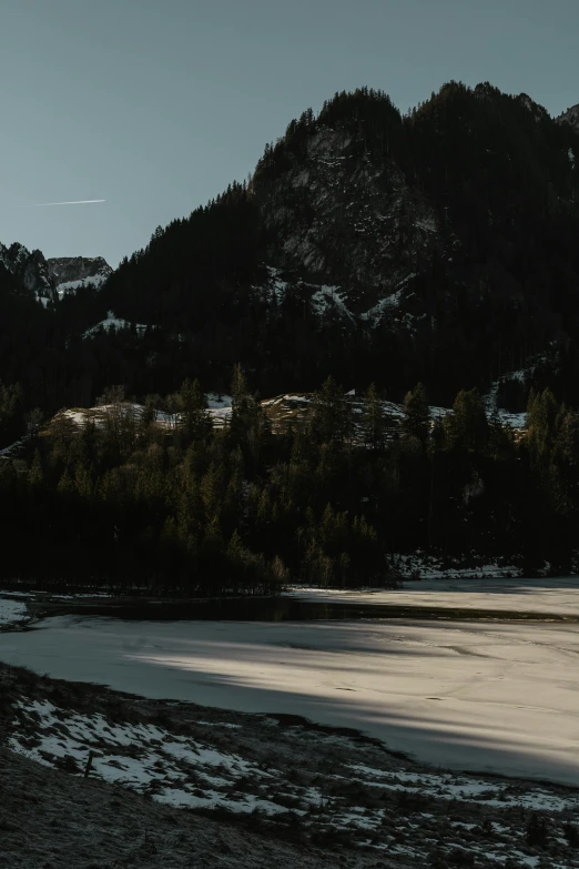 an empty beach sits next to snow covered mountains