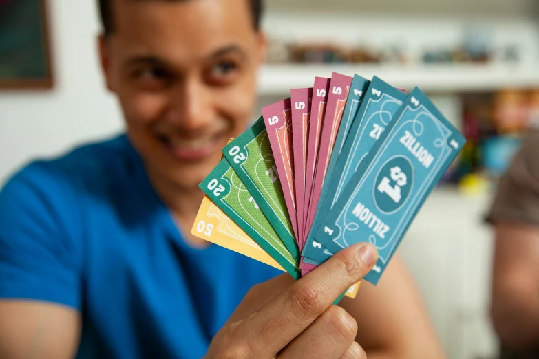 a man holding onto five multi - colored cards
