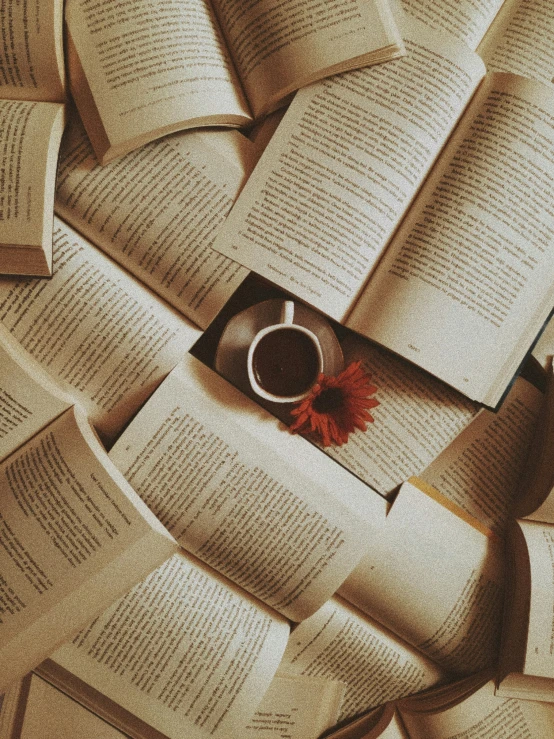 several open book laying next to a cup of coffee on top of each other