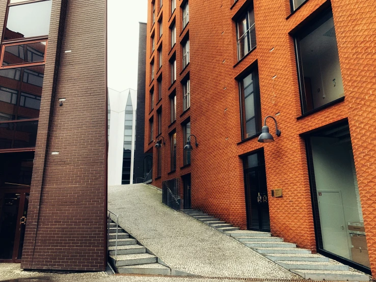 two orange brick buildings with a sidewalk on each of them