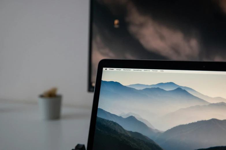 a person holding an iphone with the macbook pro on the screen