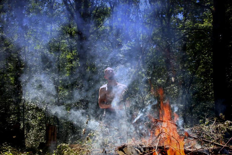 man standing in front of fire and some trees