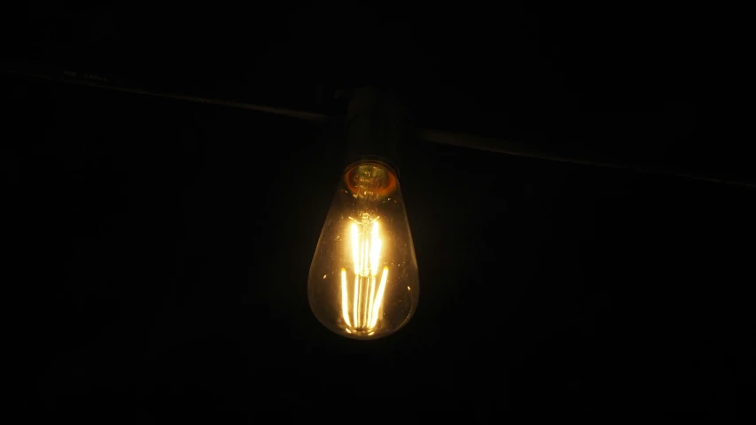 an old style light bulb that is turned on in the dark