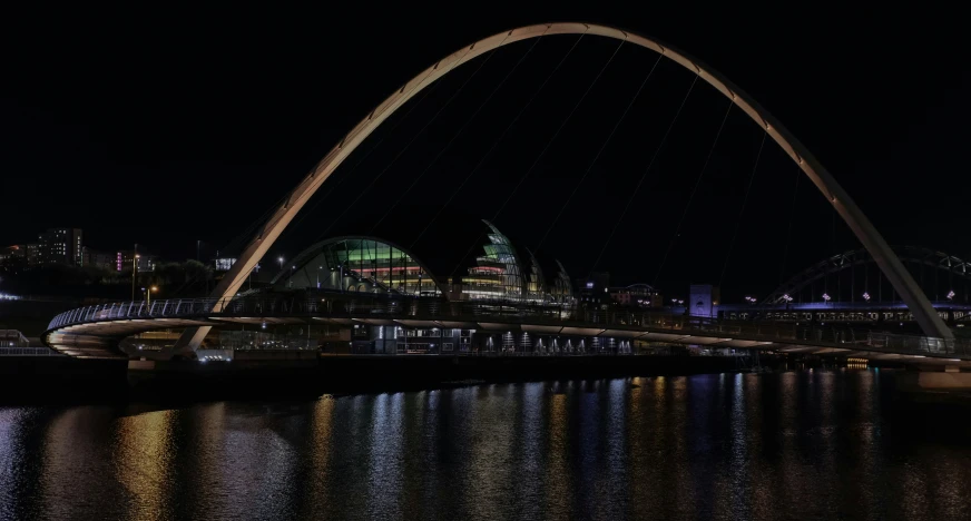 the tyne bridge illuminated at night with lights reflecting on the water