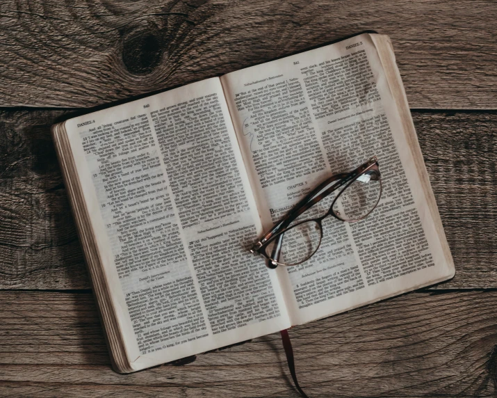 an open book on a wooden table with glasses