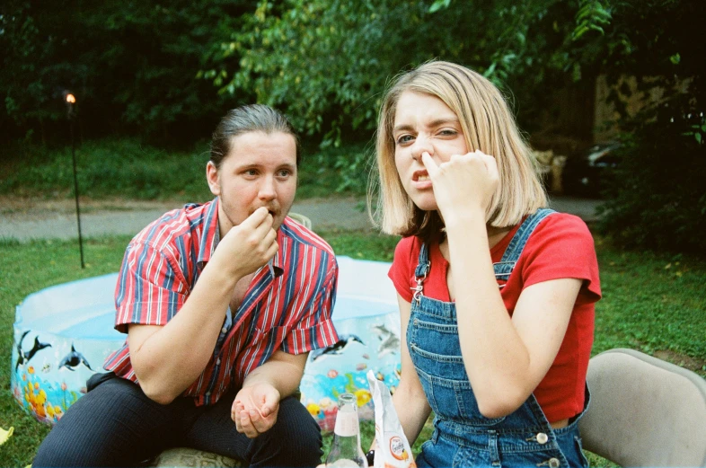 a man and a woman are eating food outdoors