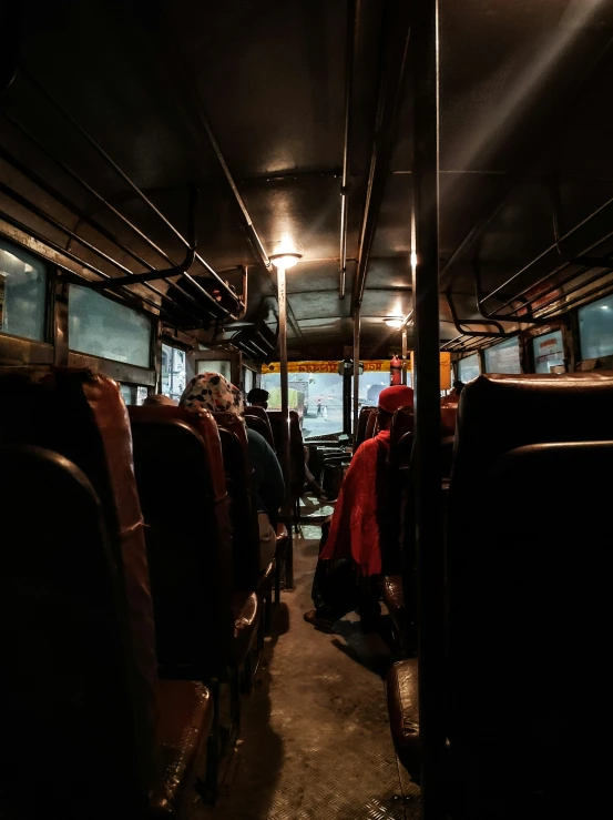 passengers sitting in a bus at night with only one person visible