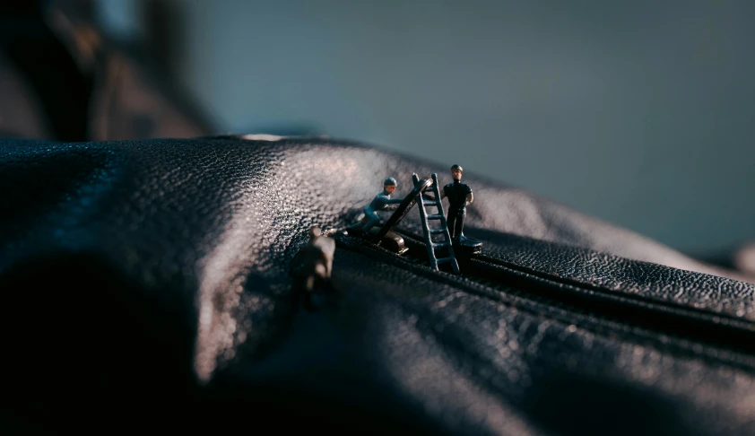 a miniature man standing on the inside of an open black purse