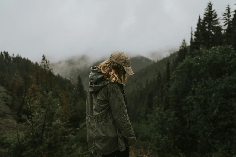 the woman is standing on top of the hill overlooking the fog