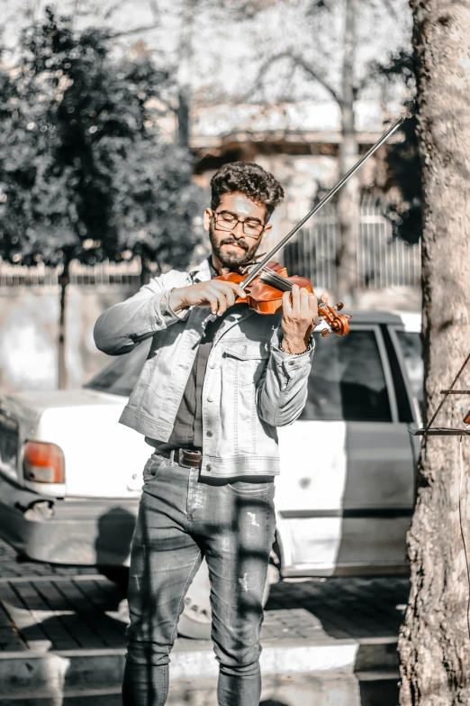 a man with glasses playing violin on the street