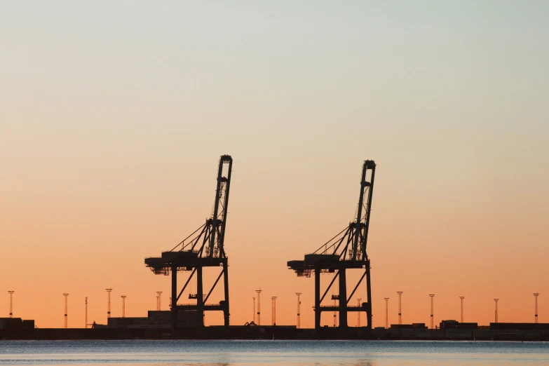 two cranes are shown against the sunset sky