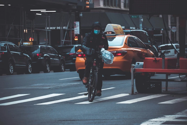 a man on his bicycle crosses the street in traffic