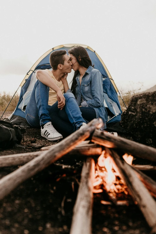 a man and woman are sitting outside a tent