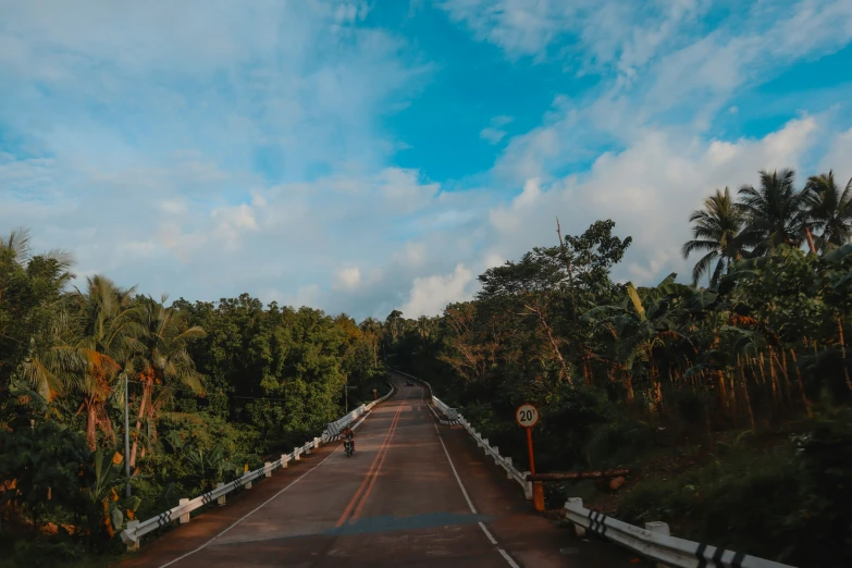 an open highway with trees and clouds in the background