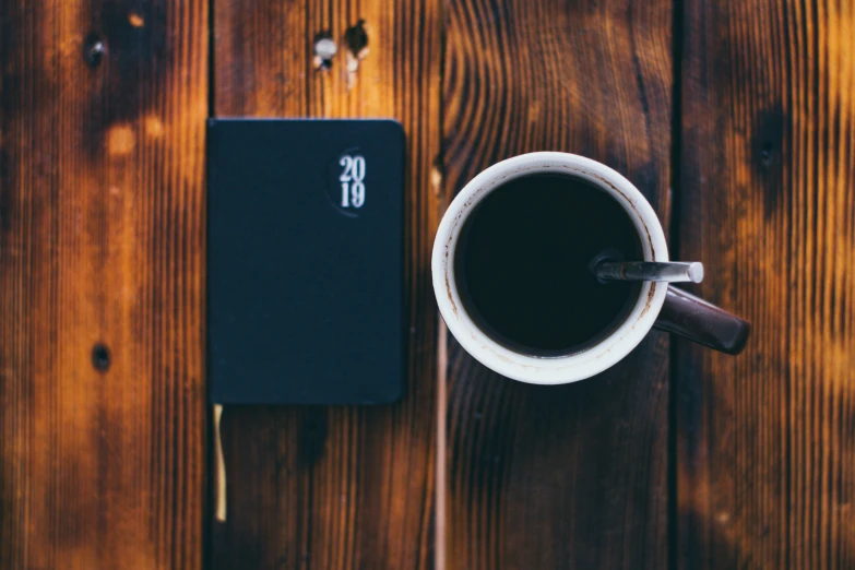 a note book is next to a coffee mug