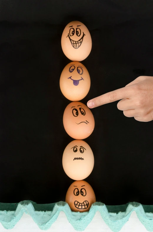 a person pointing at five eggs in different stages