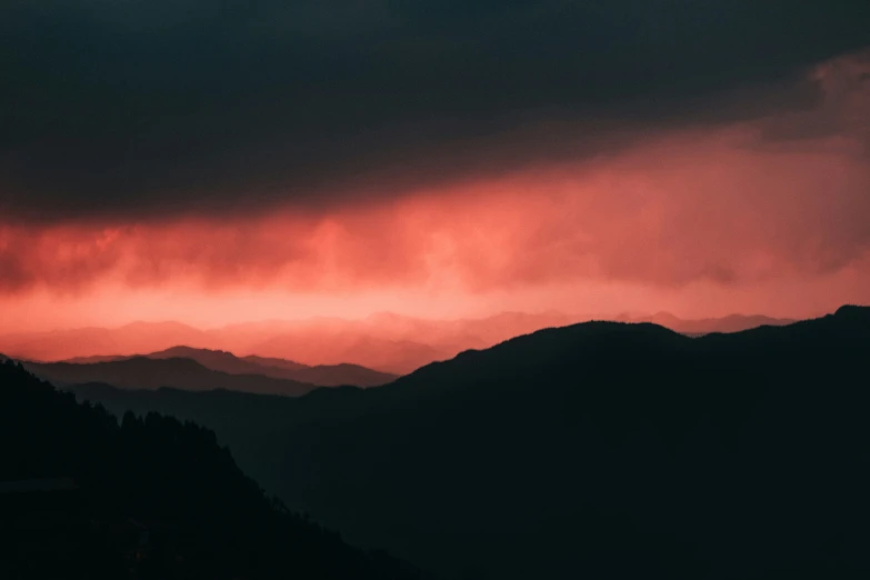 mountains covered in trees with clouds and a red light