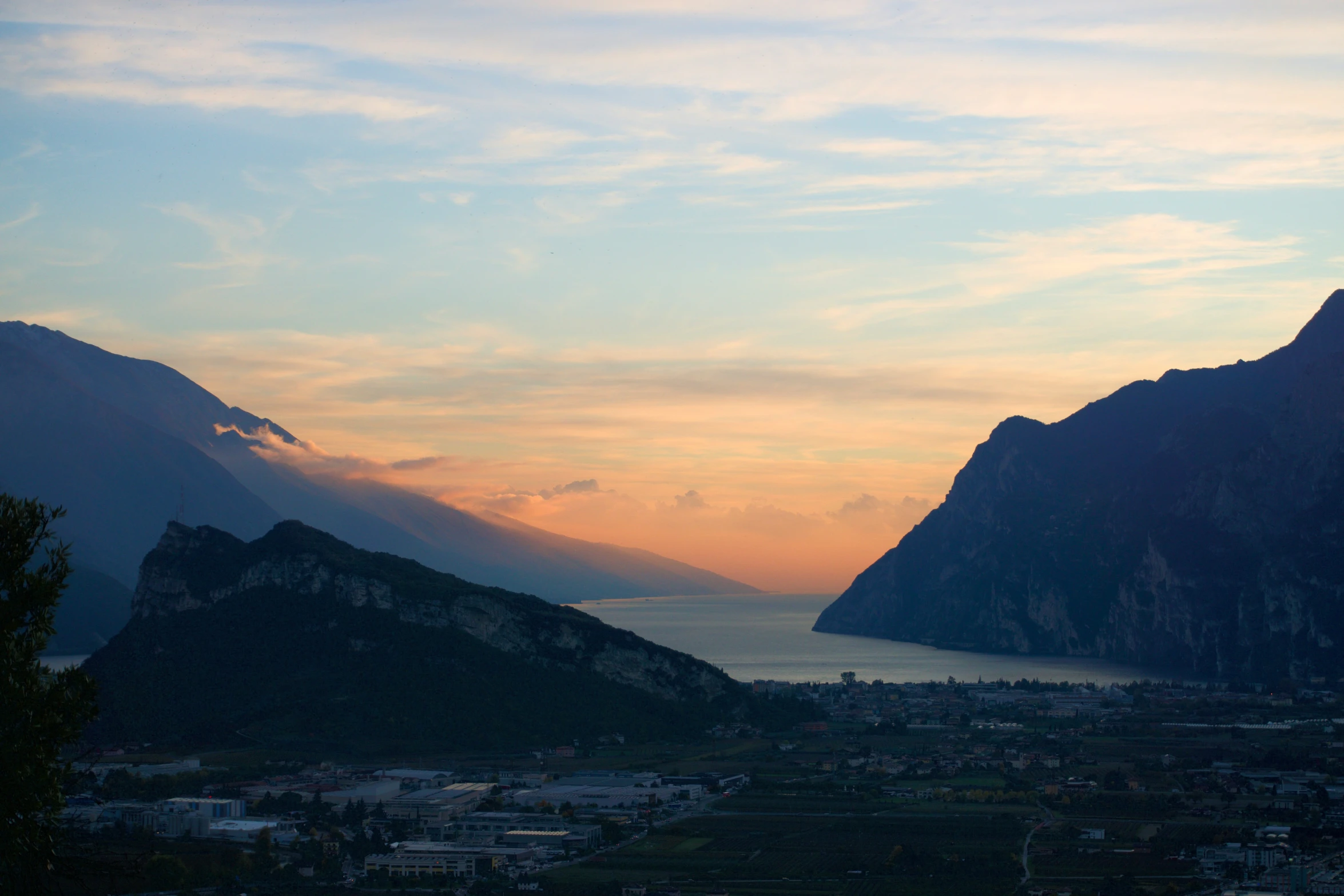 the sun is setting in between mountains and the sea