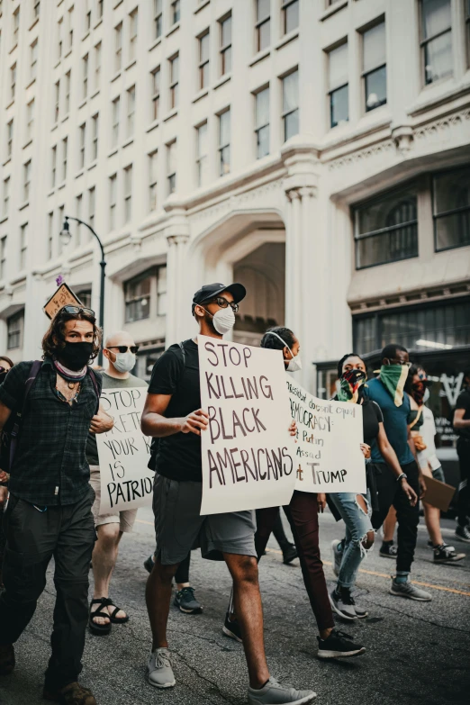 protesters in the street holding signs, including stop raging black americans