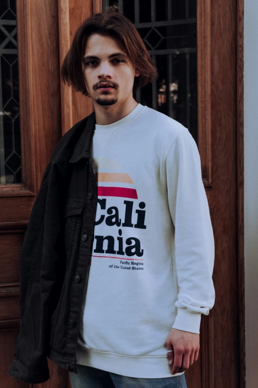 a man in a white sweatshirt is standing by a door