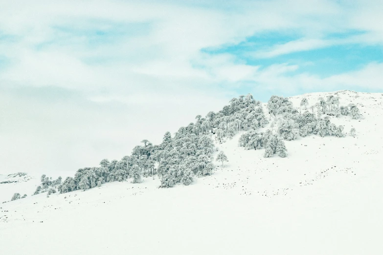 a mountain covered in snow under a cloud filled sky