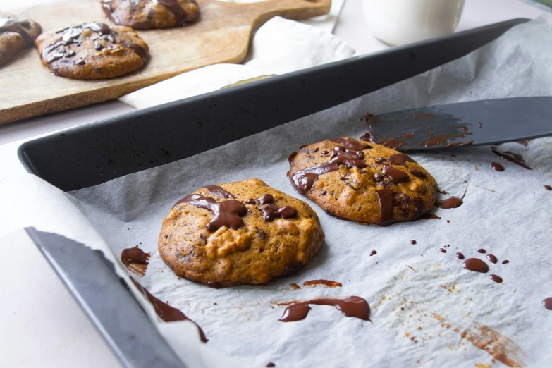 two chocolate chip cookies with a knife on the table