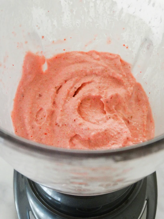 a red substance is in a glass bowl on a digital scale