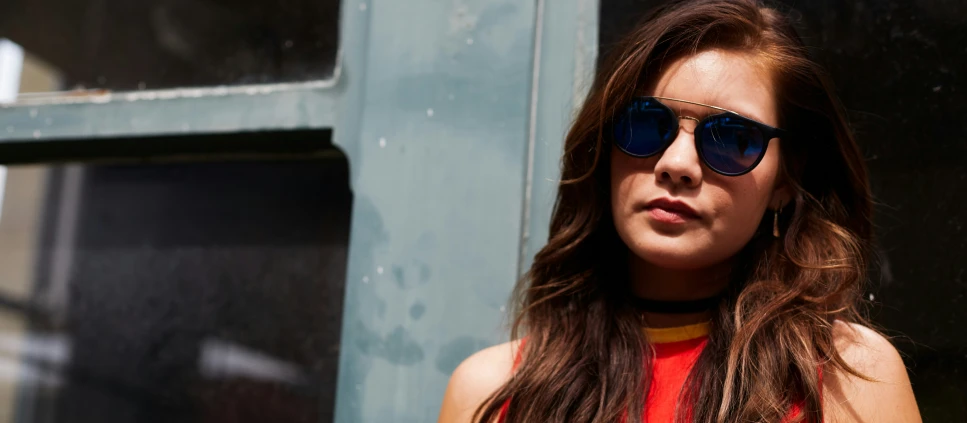 a woman wearing sunglasses leans against a door