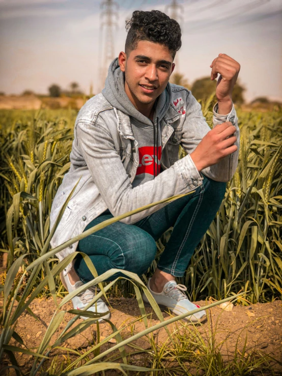 a young man crouching in a corn field