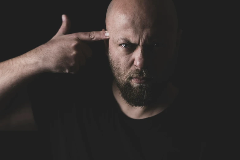 a man with a bald head and fingering his temples