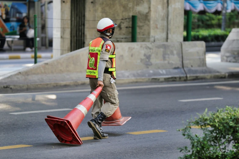 construction worker with cone is carrying object down the street
