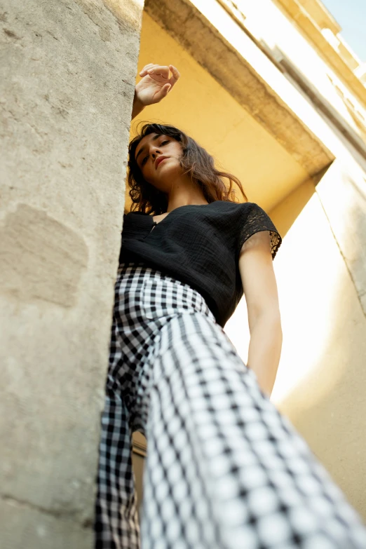 woman in black and white outfit leaning against the corner of a building