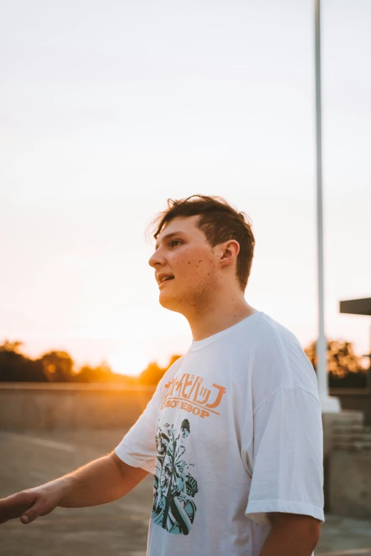 a teenage boy standing in front of a building at sunset