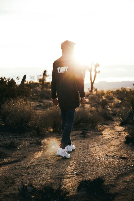 person with a hoodie walking through an open desert