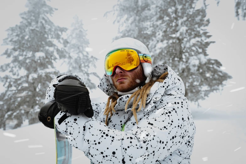 a snowboarder with dreadlocks holding onto his skis in the snow