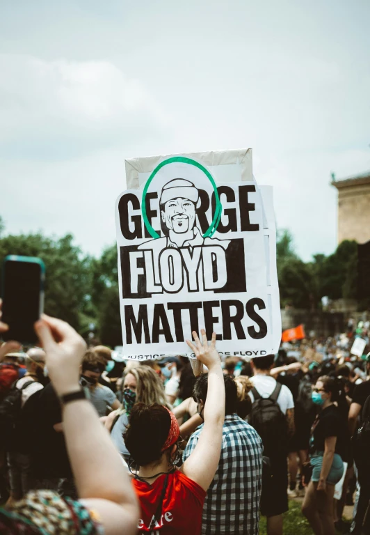 a crowd at a protest, with some holding up signs