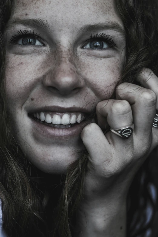 a woman smiles while holding her hand on her face