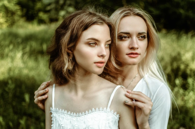 two beautiful women wearing white dress posing for the camera