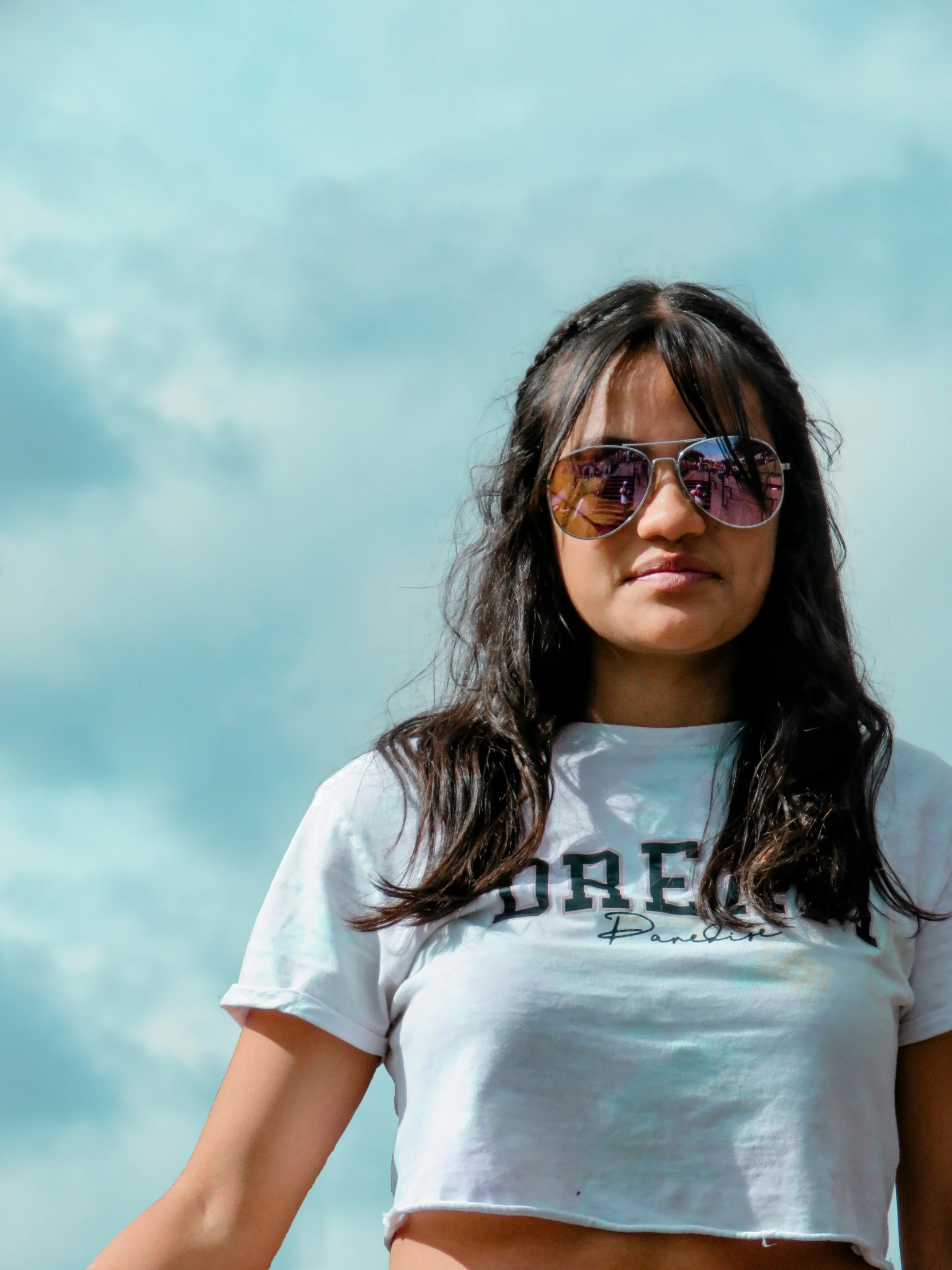 a girl with sunglasses on standing in front of blue sky