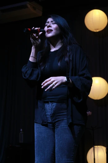 a woman in a black jacket singing into a microphone